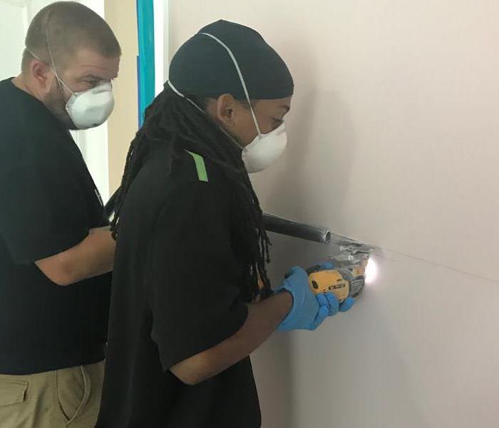 SERVPRO technicians working on removing drywall affected by water