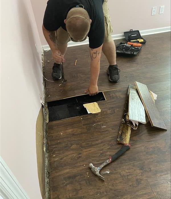 A SERVPRO employee with a mask removing damage flooring from a water damage event